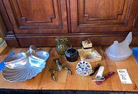 Full view of all items in the lot on the floor including the chip and dip tray, brass lobster, glass pitcher, marble paperweight, candy dish, hen dish, bottle openers