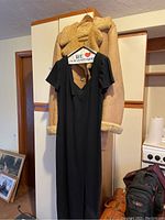 Photo of Wallachs winter coat with shearling collar and cuffs, and Liz Claiborne petite black dress size 12 hanging on door.