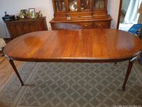 Top view of the dining table in a narrower form without leaves extended, showing polished wood surface and carved legs.