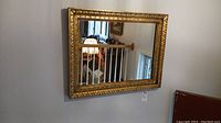 Front view of rectangular framed mirror hanging on wall reflecting room interior.