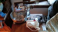 Sunbeam Mix Master stand mixer with chrome finish, mixing bowl, and attached mixing blades on tabletop.