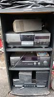 Full photo showing stereo system stacked in a cabinet including CD player, receiver, cassette deck, and speakers on top and bottom shelves.