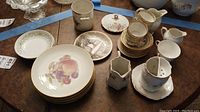 Overview of dessert plates, teacups, creamers, and additional small plates and vases on table