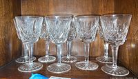 Group of eight stemmed crystal wine glasses on wooden shelf