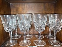 Eight clear crystal water glasses arranged in two rows showing the diamond and wedge cut patterns and starburst bases.