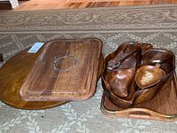 Wood trays and bowls arranged on rug. Dolphin genuine teakwood rectangular tray with metal ring handle, large wooden tray with handles, and sectioned wooden bowl visible.