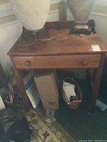 Front view of vintage maple side table with drawer, showing scratches on surface and wooden knob.