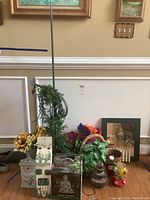Wide view of the lot including artificial greenery, sunflower vase, vintage lamp, water fountain with Buddha figure, felt flowers, and basket on floor.