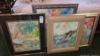 Four framed interpretive landscape paintings placed against couch and wall, displaying different frame styles and abstract landscape artwork.