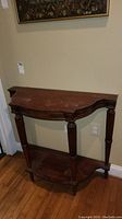 Front view of demi lune hall table showing stained top surface and scalloped wooden edge