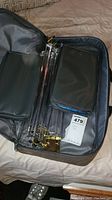 Opened black carrying case showing compartments and clear plastic divider with gold-colored latches.