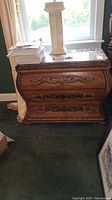 Front view showing bombe profile, carved appliqués and metal bail handles.