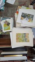 Multiple original unframed paintings arranged on a table, showing abstract landscape styles with diverse color palettes.