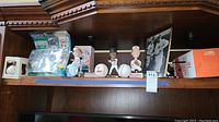 Full view of shelf with signed baseballs, action figures, bobbleheads, and framed baseball photograph.