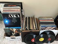 Photo showing multiple vintage vinyl records including Anka's Times of Your Life, Tom Jones, and others in boxes with loose records.