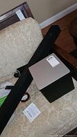 Soundbar, wireless subwoofer, and part of surround speakers on a couch.