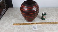 Pottery vase alongside a ruler and soda can for scale, showing overall shape and size