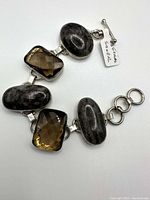Full view of the bracelet showing dark oval agate stones and rectangular faceted topaz stones mounted in silver with toggle clasp.