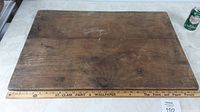 Top view of the antique wooden dough/bread board showing the wood grain, knots, and surface wear with a ruler at the bottom for scale.