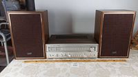 Full view of Studio-Standard by Fisher RS-1035 stereo receiver centered between two Panasonic SB-66 speakers on a white tablecloth.