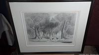 Framed etching depicting a forest scene with figures sitting under the trees, visible signature and date in lower left corner.