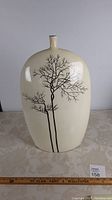 Full front view of the tall cream-colored ceramic vase with black painted tree branches.