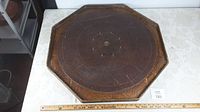Top-down photo of the octagonal wooden Crokinole board, showing the entire playing surface, rim, and wood grain details.