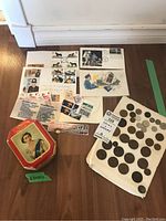 Overall photo of collection showing loose coins, postage stamps, commemorative envelopes, and red EIIR 1953 Coronation tin box