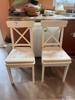 Front view of two white Ikea Ingolf chairs with tufted cushions in kitchen setting