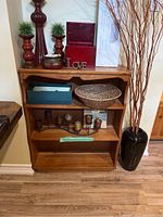 Full view of three tier wooden shelf with various decorative items on and around it.