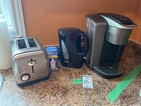 Photo shows arranged small appliances on countertop: Salton toaster, Chef electric kettle, Brita water filter box, and Keurig coffee maker.