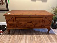 Front view of solid wood trunk showing carved pattern and legs