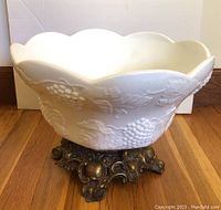 Full view of white milk glass punch bowl with embossed grape clusters and leaves on an ornate metal stand with intricate detailing.