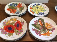 Set of 12 floral dinner plates in 4 designs shown stacked on table