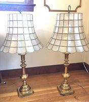 Pair of vintage Mid-Century Modern brass lamps with capiz shell shades positioned side by side, showing overall design and size.