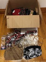 Cardboard box containing assorted fabric and interfacing, along with purse handles and fabric covers displayed in front.