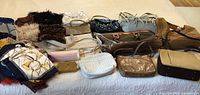 Tabletop with 16 assorted purses displayed including varied textures and colors