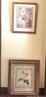 Two framed prints hanging on wall, top is Venice canal scene with yellow boat, bottom is botanical rose print.