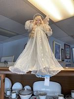 Front view of heirloom style angel doll in white dress with halo, curly blonde hair, and visible wings.