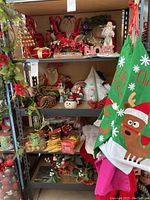 Shelves stocked with various Christmas decorations including figurines, ornaments, faux floral arrangements, and holiday-themed fabric gift bags hanging to the side.