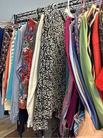 Photo showing assorted women's clothing on a rack including floral, paisley, solid, and multicolored sweaters and cardigans.