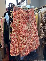 Pink and white paisley patterned skirt hanging on rack among other clothing items