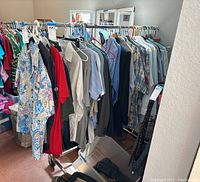 Clothing rack filled with various clothes on hangers, showing the full rack and its wheels.