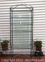 Front view of the tall metal and glass shelving unit showing all three glass shelves and the arched top detail.