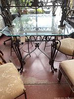 Front view of dining table showing glass top, marble inset and wrought iron base