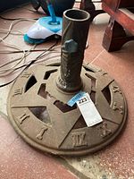 Top view of circular cast iron umbrella stand with Roman numerals and central post with tightening knob
