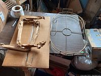 Metal bed tray frame with foldable legs wrapped in paper, glass base removed and placed separately.