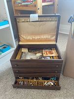 Wooden jewelry box open showing top compartment, interior hooks and two drawers