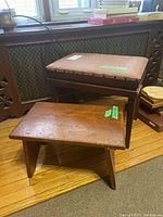 Front view of cushioned bench and wood stool on hardwood floor near heater cover under window