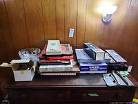 Wide view of all items including serving plates, glass bowl, stacked boxes and cutlery on wooden table against wall